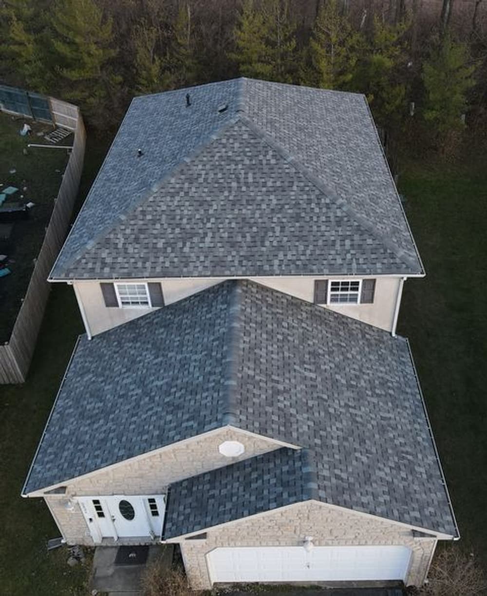 Aerial view of a modern house with a gray shingle roof and a landscaped yard.