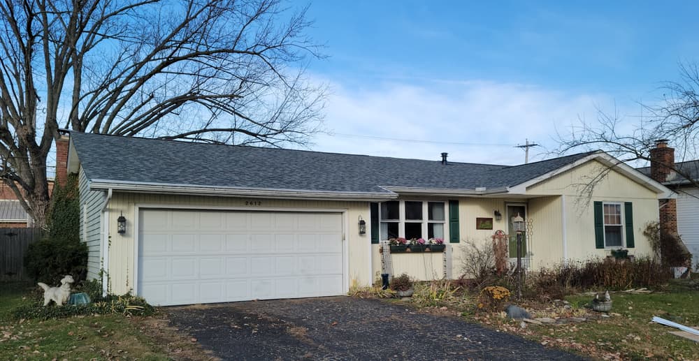 Single-story suburban home with a garage, landscaped yard, and clear blue sky.