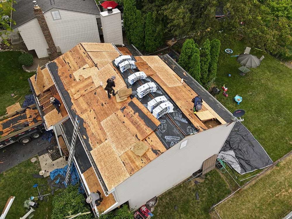 Aerial view of a residential roofing project with workers installing shingles.
