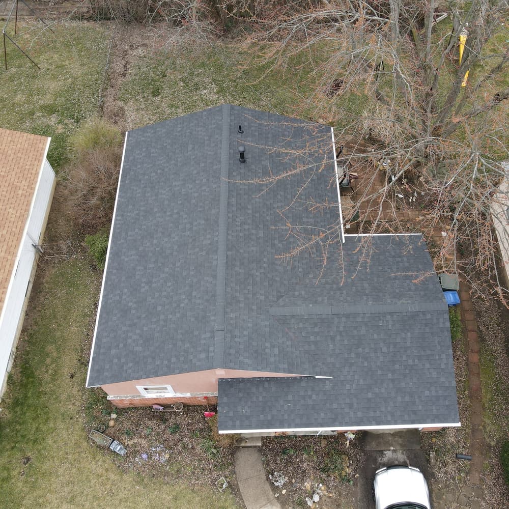 Aerial view of a residential house with a gray roof and surrounding yard.