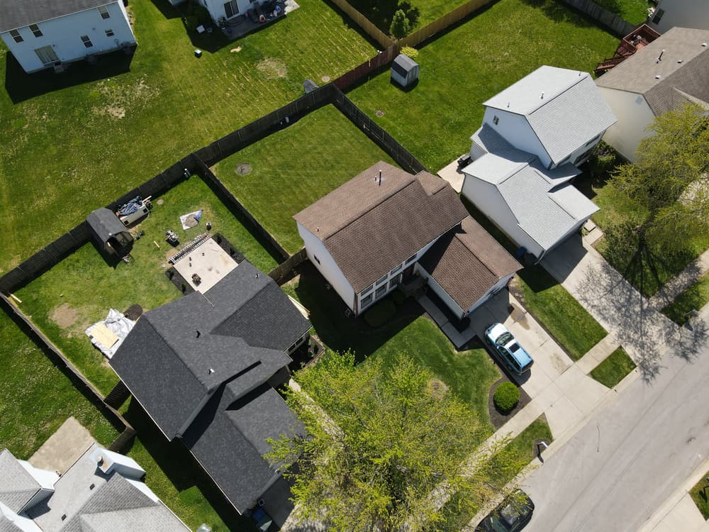 Aerial view of suburban homes with green lawns and driveways on a sunny day.