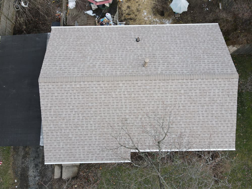 Aerial view of a residential home roof featuring shingles and a vent pipe.
