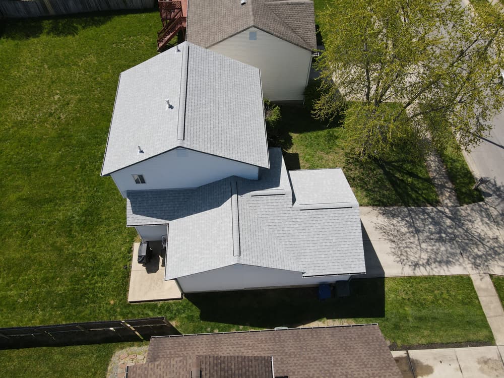 Aerial view of a residential home with gray roofs and green lawn.