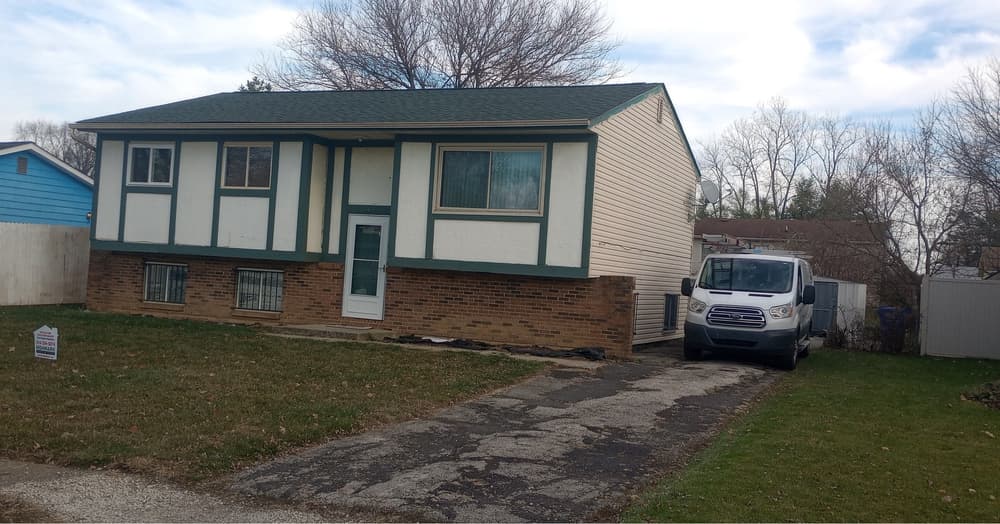 Single-family home with a green roof and brick façade, parked van on the driveway.