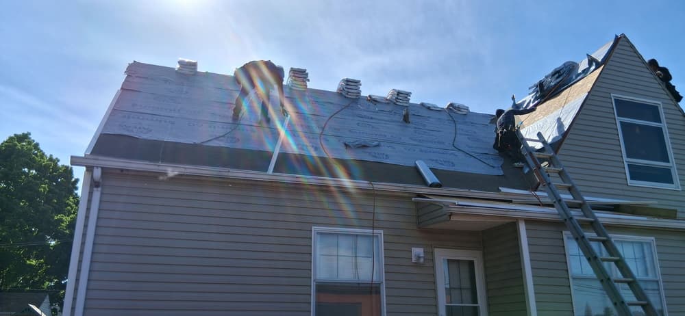 Roofing project in progress on a residential home with shingles and a ladder.